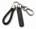 A black leather braided keychain loop attached to a black plastic bar with white numbers 1 through 0, connected to silver metal key rings and a carabiner clip on a white background.